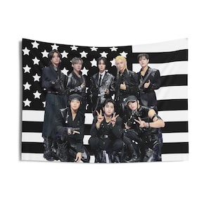Puede incluir: Un tapiz en blanco y negro con un grupo de nueve personas posando frente a un diseño de la bandera estadounidense. Las personas visten trajes negros. El tapiz es rectangular y cuelga de una pared blanca.