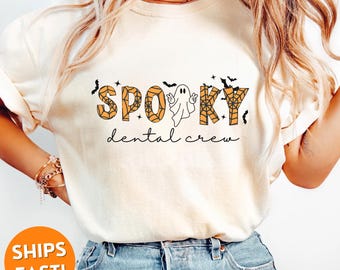 May include: Cream-colored sweatshirt with the words "SPOOKY dental crew" in black script. The word "SPOOKY" is in orange and black, with a ghost and bats. A Halloween-themed graphic tee.
