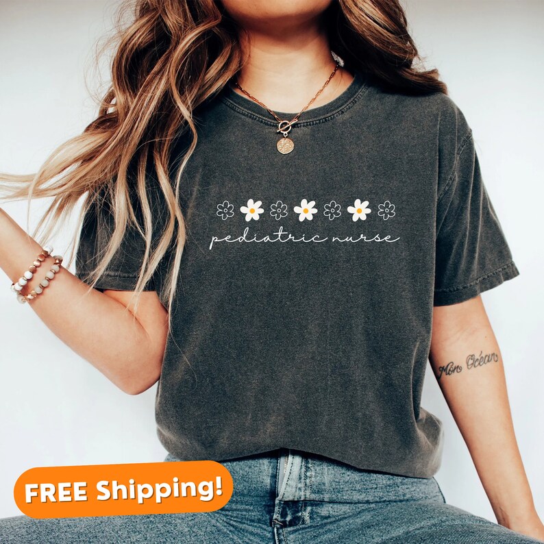 May include: A dark grey t-shirt with a white daisy chain and the text "pediatric nurse" printed on the front.