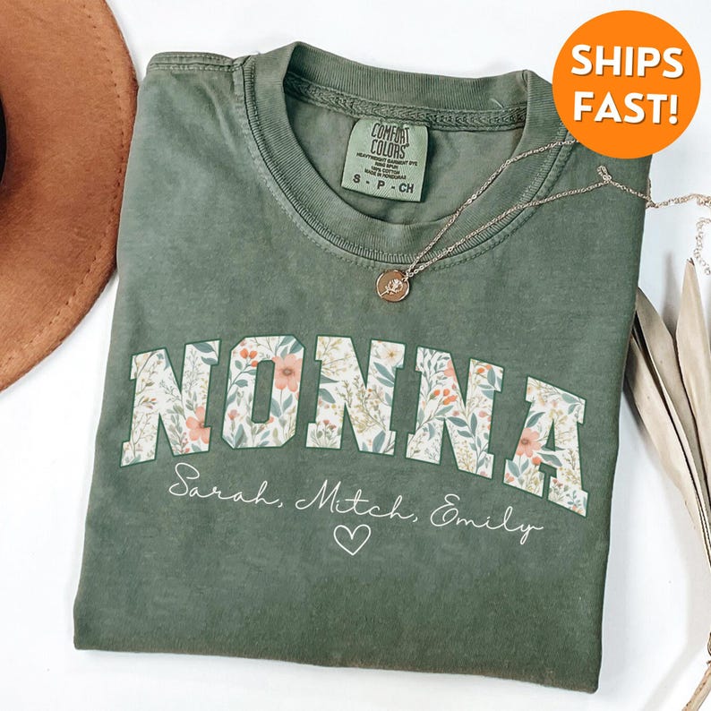May include: Green t-shirt with a floral design and the word "NONNA" in large letters. The shirt also has the text "Sarah, Mitch, Emily" and a heart.