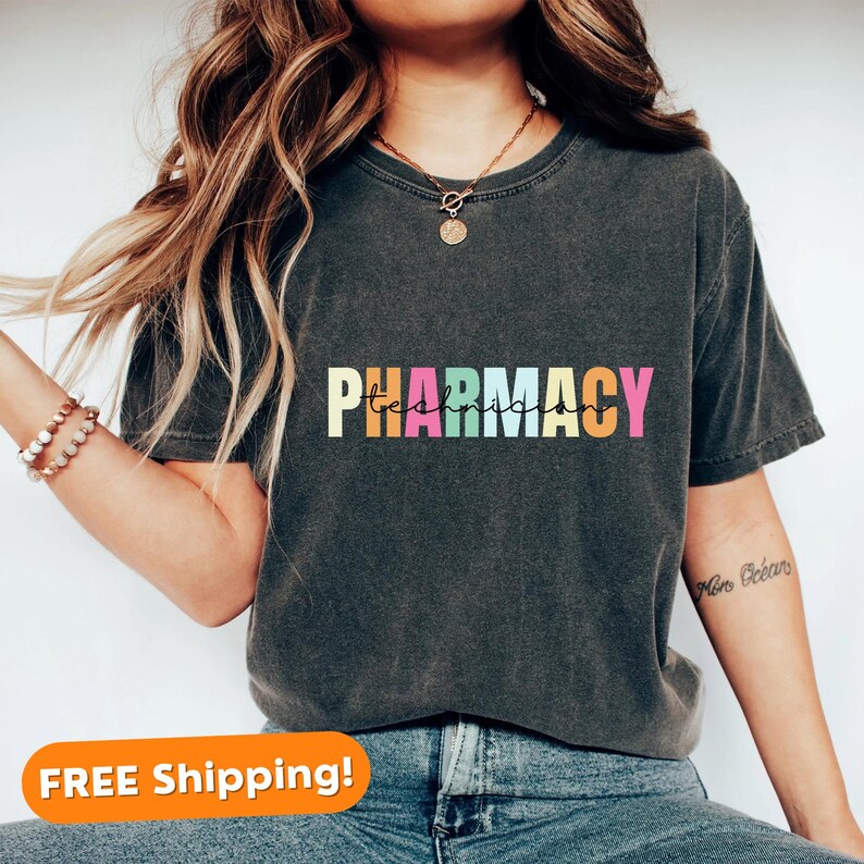 May include: A dark grey t-shirt with the text "PHARMACY Technician" in rainbow colours. The text is in a casual, handwritten font.