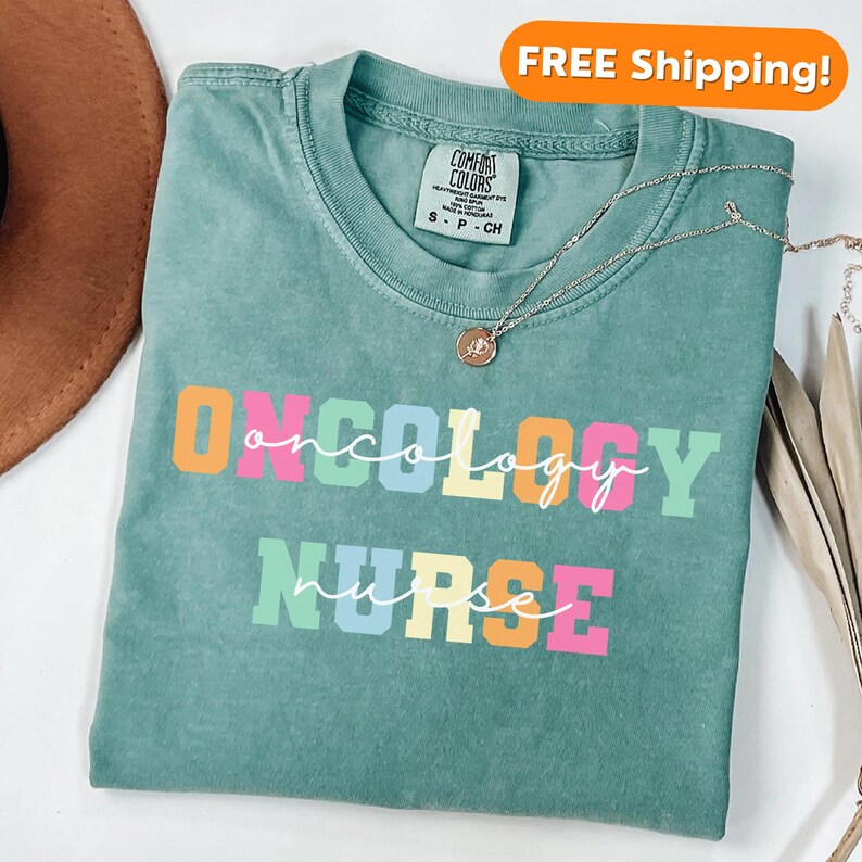 May include: A teal blue t-shirt with the words "ONCOLOGY NURSE" in rainbow colored letters. The shirt has a distressed look and is made of a soft, comfortable material.