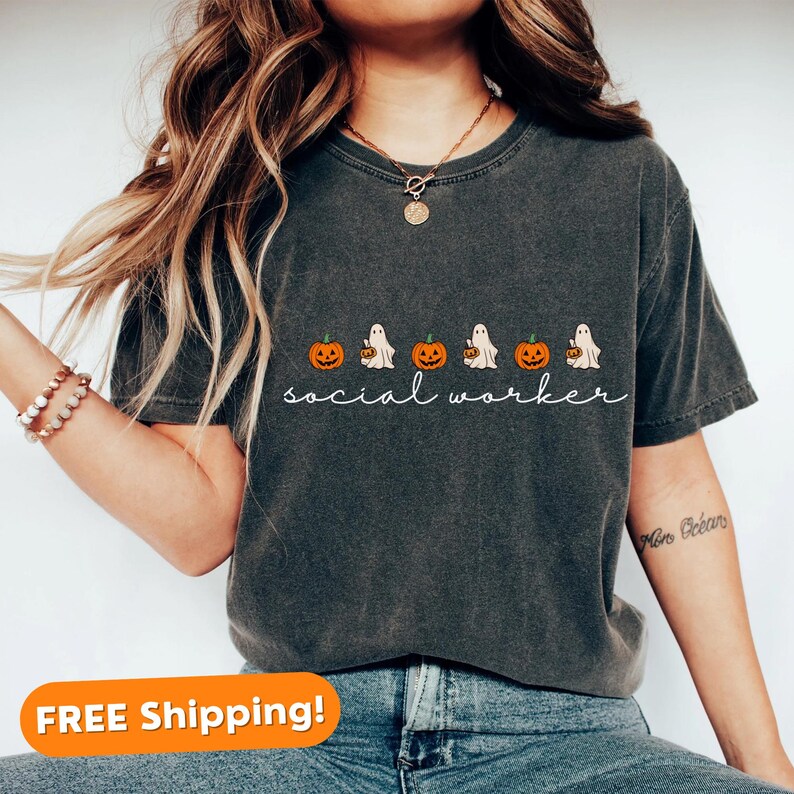 May include: A dark gray t-shirt with a Halloween-themed design featuring ghosts carrying pumpkins and the text "social worker".