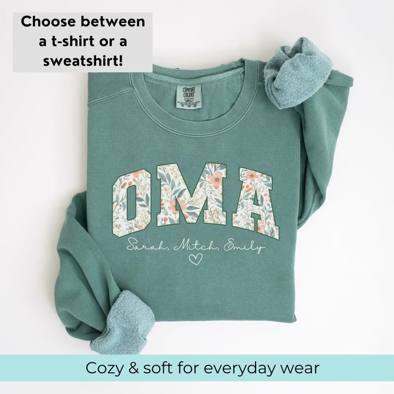 May include: A teal green sweatshirt with the word "OMA" in white letters with a floral pattern. The names "Sarah, Mitch, Emily" are written below the word "OMA" with a heart symbol.