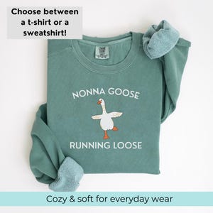 May include: A teal sweatshirt with the text "NONNA GOOSE RUNNING LOOSE" and a cartoon goose illustration. The top text reads "Choose between a t-shirt or a sweatshirt!" and the bottom text reads "Cozy & soft for everyday wear."