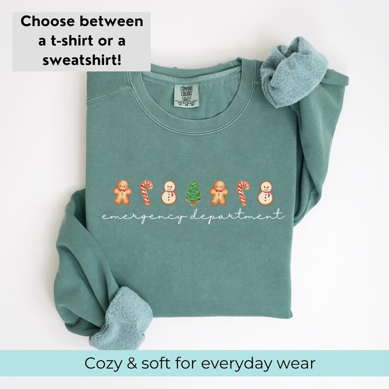 Puede incluir: Una sudadera de color verde azulado con un dise&ntilde;o navide&ntilde;o. El dise&ntilde;o presenta hombres de jengibre, bastones de caramelo, mu&ntilde;ecos de nieve y &aacute;rboles de Navidad. El texto "emergency department" est&aacute; escrito debajo del dise&ntilde;o.