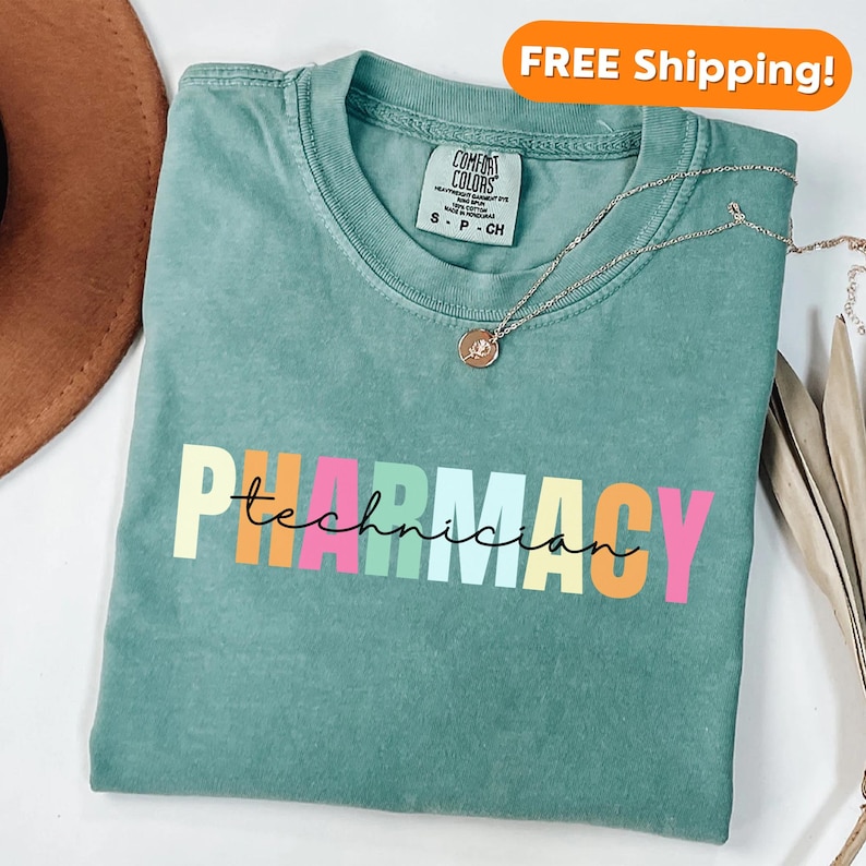May include: A teal blue t-shirt with the words "Pharmacy Technician" in rainbow colours. The text is in a script font.