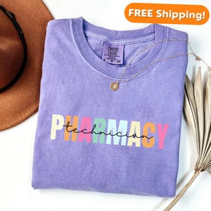 May include: A purple t-shirt with the text "PHARMACY technician" in rainbow colours. The text is in a playful font.