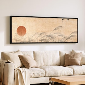 May include: A rectangular wall art piece in a black frame featuring a beige textured background with a large orange sun on the left, black silhouettes of tall grasses in the foreground, and two small black birds flying in the upper right.