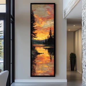 May include: A tall, vertical rectangular framed painting depicting a sunset over a calm lake. The scene features dark silhouettes of pine trees against a vibrant sky filled with orange, yellow, and red hues, with the reflection visible in the water.