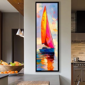 May include: A colourful painting of a sailboat with a blue hull and orange and pink sails. The artwork is framed in black and reflects on the water. The background features a sky with clouds.