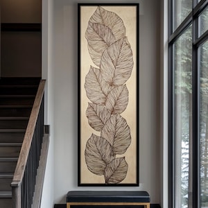 Puede incluir: Obra de arte vertical enmarcada que presenta una serie de hojas marrones estilizadas sobre un fondo beige. Las hojas tienen patrones de venas detallados y están dispuestas en una composición vertical superpuesta. El marco es negro.