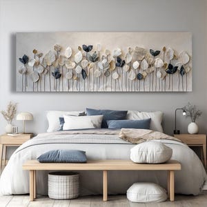a modern bedroom with a large bed, wooden nightstands, and a wooden bench. The bed is covered in white and gray bedding, and the room features a large wall art piece with a repeating pattern of leaves and flowers.