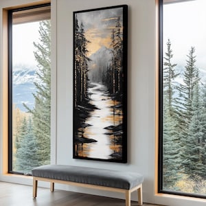 Può includere: Un dipinto astratto verticale che rappresenta una scena di foresta con un fiume che scorre attraverso di essa. Il dipinto è realizzato in tonalità di nero, bianco e oro, con una montagna sullo sfondo. Il dipinto è incorniciato in nero.