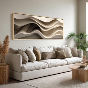 May include: A modern living room featuring a large, framed abstract art piece with flowing, wave-like forms in shades of beige and brown. A white sofa with various throw pillows sits below the artwork. A round wooden coffee table and a woven basket add to the room's decor.