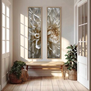 May include: Two vertical rectangular wall art pieces featuring a close-up, detailed view of white and cream-colored dahlia flower petals. Each piece is encased in a thin, light-toned wooden frame, displaying soft shadows and intricate textures.