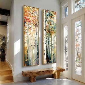 Può includere: Due dipinti verticali incorniciati raffiguranti alberi stilizzati con fogliame colorato. I dipinti presentano una tavolozza di tonalità arancioni, rosse, verdi e gialle. L'opera d'arte è esposta su una parete bianca, con una panca in legno sottostante.