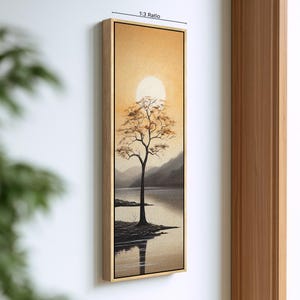 May include: A vertical rectangular canvas print in a light wood frame featuring a landscape painting of a lone tree on a shoreline against a golden sunset and a large white sun. The artwork displays a 1:3 ratio label at the top edge.