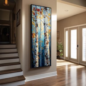 May include: A tall, rectangular framed painting depicting a forest scene with vertical tree trunks in shades of white, gray, and blue. The composition features textured brushstrokes of yellow, orange, and red leaves scattered throughout the branches.