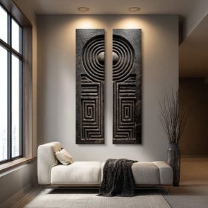 May include: Two tall, rectangular wall art panels featuring a dark, textured surface with carved geometric patterns. Each panel displays a series of concentric circles at the top and a square labyrinthine design below, creating a symmetrical visual effect.
