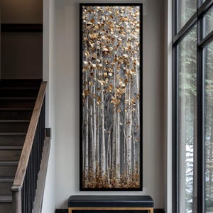 May include: Vertical framed artwork depicting a stylized forest scene. The painting shows slender, white birch tree trunks with gold-coloured leaves against a grey background. The artwork is framed in black and hangs above a black bench.
