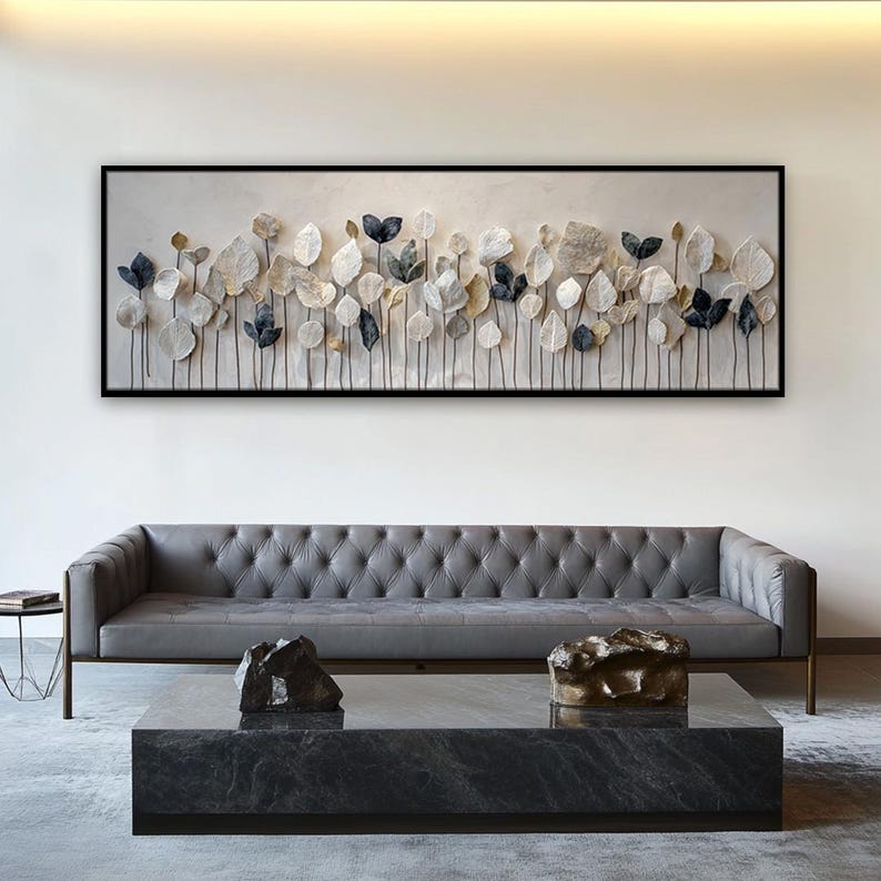 a modern living room with a gray tufted sofa, a black marble coffee table, and a large framed artwork hanging on the wall above the sofa.