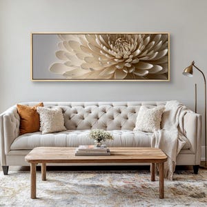 May include: A cream-coloured floral artwork in a gold frame, displayed above a buttoned sofa. The image shows a living room setting with a wooden coffee table and decorative cushions. The artwork's dimensions are in centimetres.