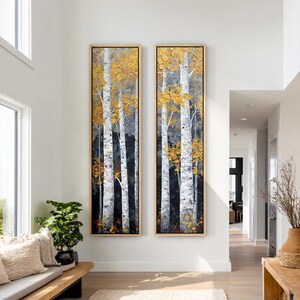 May include: Two tall, vertical rectangular wall art pieces in light wood frames, depicting a forest of white birch trees with textured, thick-applied golden yellow leaves against a dark, moody background, displayed side-by-side on a white wall.
