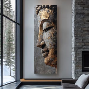 Può includere: Una grande opera d'arte murale verticale raffigurante un profilo dettagliato del volto di Buddha. La scultura ha un aspetto metallico usurato con accenti dorati. Lo sfondo è grigio tenue e l'opera d'arte è esposta in un moderno spazio abitativo.