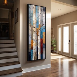 May include: A tall, rectangular framed wall art piece featuring a vertical composition of white birch tree trunks set against a background of overlapping geometric color blocks in shades of blue, orange, red, and gray, with bare branches extending outward.