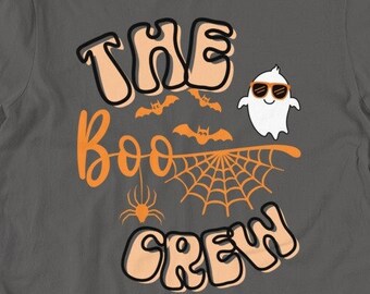 May include: A charcoal gray short-sleeve t-shirt featuring a graphic print with the text "THE BOO CREW" in a retro font. The design includes a white ghost wearing orange sunglasses, orange bats, a spider, and a spiderweb on a gray background.