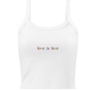 May include: White crop top with thin straps. The phrase "love is love" is embroidered in rainbow colors across the front. The top is a casual style, suitable for warm weather.