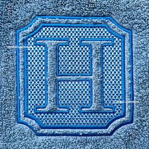 May include: A blue embroidered letter H on a light blue textured background.