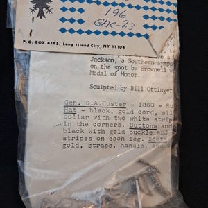 Peut inclure: Un ensemble de figurines miniatures dans un sac en plastique transparent. L'emballage comprend le logo Monarch Miniatures Inc., le code produit 196 GAC-63, et le texte décrivant la figurine comme Gen. G.A. Custer, 1863.