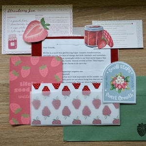 May include: A collection of stationery items with a strawberry theme. Includes a recipe card, a jar of jam illustration, a card with the text "Life is good water", a sticker with the text "Small Steps Sweet Growth", and a green envelope with a strawberry stamp.