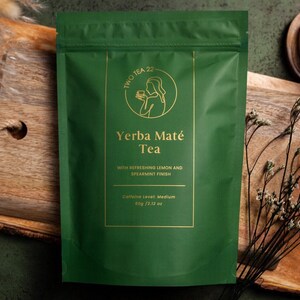 May include: A green pouch with a gold label that reads "TWO TEA 22" and "Yerba Maté Tea" with a gold illustration of a person holding a cup. The label also says "With refreshing lemon and spearmint finish" and "Caffeine level: Medium 80g / 2.12 oz".