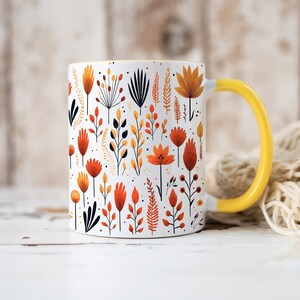 May include: A white ceramic mug with a yellow handle features a colorful floral pattern in shades of orange, yellow, and red. The mug is filled with a floral design of stylized flowers and leaves.