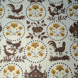 K&ouml;nnte beinhalten: Cremefarbener Stoff mit einem sich wiederholenden Muster aus braunen H&auml;hnen, V&ouml;geln, H&auml;usern und gelben Blumen. Das Design ist in gepunkteten Kreisen eingeschlossen und erzeugt eine Vintage-Bauernhaus-&Auml;sthetik. Der Stoff hat ein strukturiertes Aussehen.