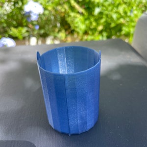 May include: A small, blue, 3D printed planter with a ribbed design.