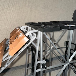 May include: A grey and black plastic structure with a brown ramp. The structure has a grid-like top and is made of multiple connected pieces.