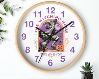 Peut inclure: Horloge murale ronde avec un cadre en bois clair. Le cadran de l'horloge présente un motif de sorcière violet et noir avec le texte "THE WITCHING HOUR" et "WHEN THE WITCHES COME OUT TO PLAY". Les chiffres sont violets.