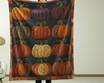 May include: A large, rectangular blanket featuring a repeating pattern of colorful pumpkins in shades of orange, purple, and brown against a dark background. The blanket has a decorative border with orange and brown stripes. The pumpkins have green stems.