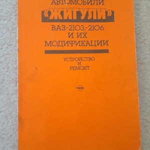 Puede incluir: Un libro naranja con texto en ruso. El título dice "Avtomobili Zhiguli" con los números de modelo VA3-2103, 2106 y sus modificaciones. El texto inferior dice "Dispositivo y reparación."