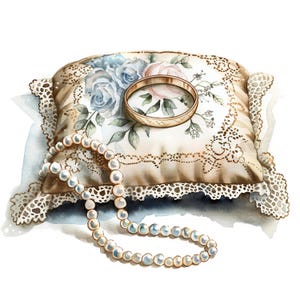 May include: A white satin pillow with lace trim and floral embroidery, topped with a gold ring and a pearl necklace.