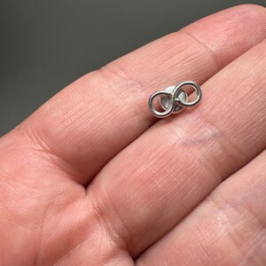 May include: A silver infinity symbol earring. The earring is small and delicate, and it is perfect for everyday wear.