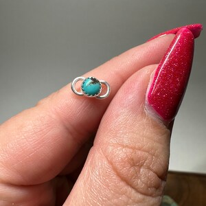 May include: A small silver ring with a turquoise stone set in the center. The ring is simple and elegant, and the turquoise stone is a beautiful shade of blue.