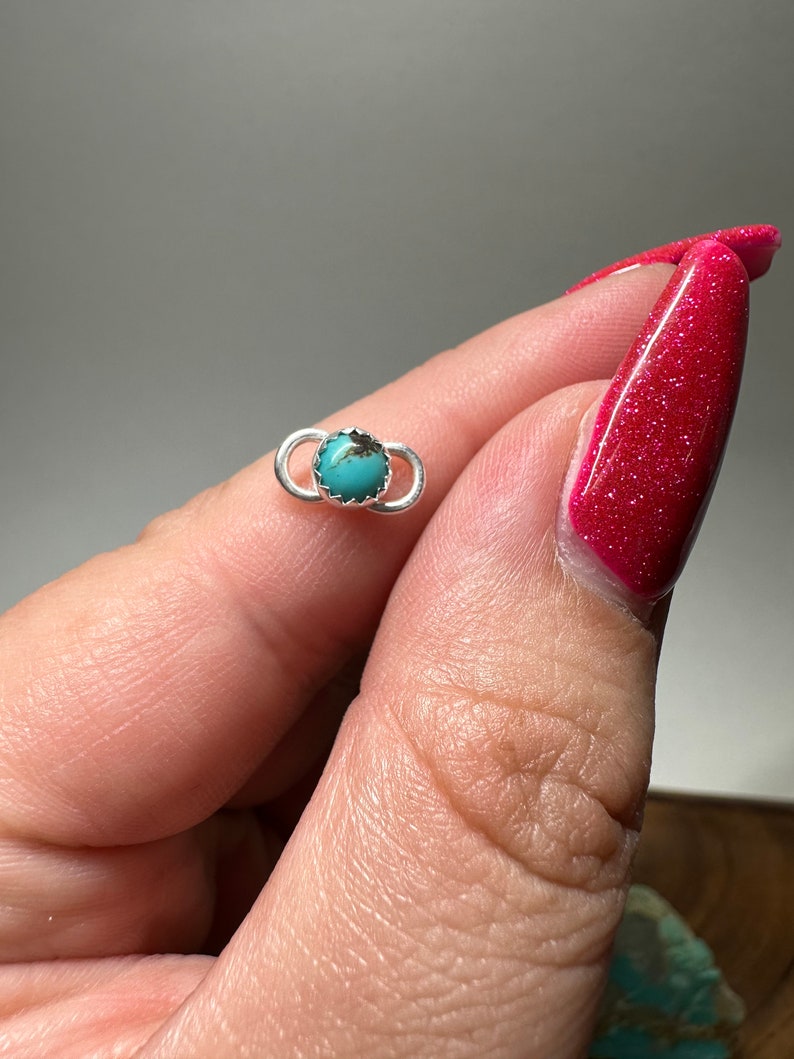 May include: A small silver ring with a turquoise stone set in the center. The ring is simple and elegant, and the turquoise stone is a beautiful shade of blue.