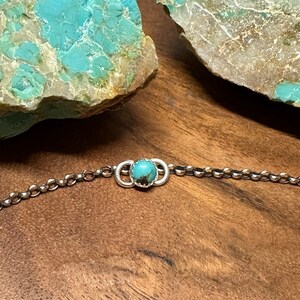 May include: A silver chain bracelet with a turquoise stone set in a silver circle.