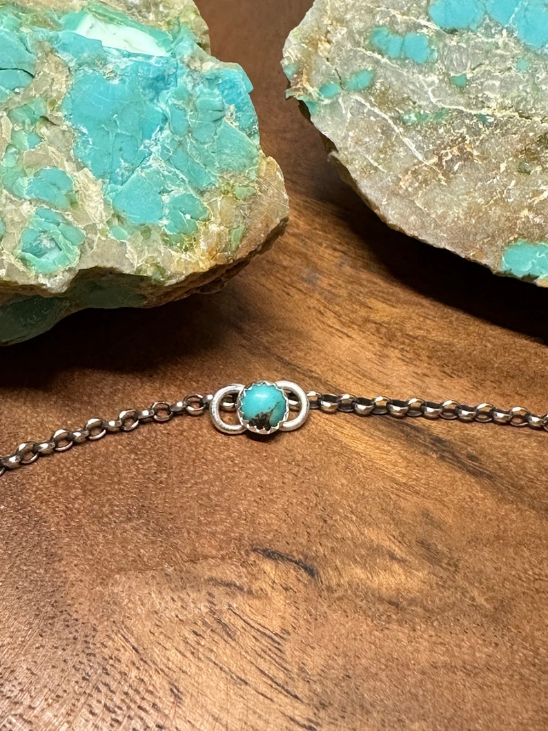 May include: A silver chain bracelet with a turquoise stone set in a silver circle.