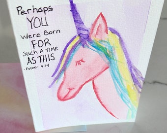 Puede incluir: Una pintura de acuarela de un unicornio con un cuerno morado y una crin arcoíris. El texto "Perhaps you were born for such a time as this - Esther 4:14" está escrito en la tarjeta.